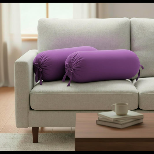 Purple cylindrical pillows on a beige sofa with a wooden coffee table in the foreground.