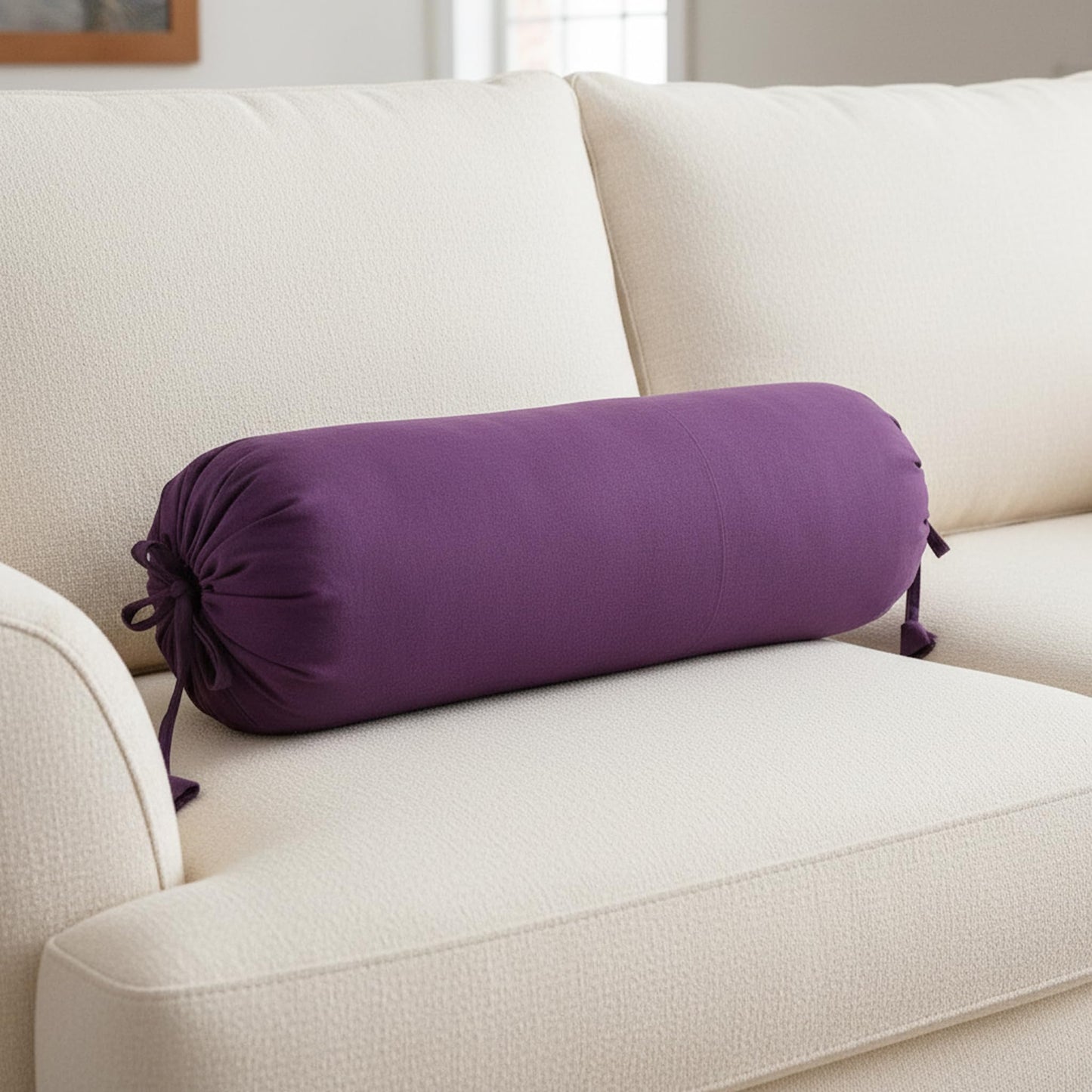 Purple cylindrical pillow on a beige sofa