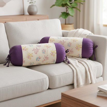 Decorative cylindrical pillows with floral patterns on a sofa in a living room setting.