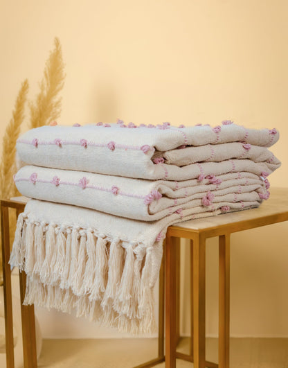 Stack of folded towels with tassels on a wooden table against a beige background