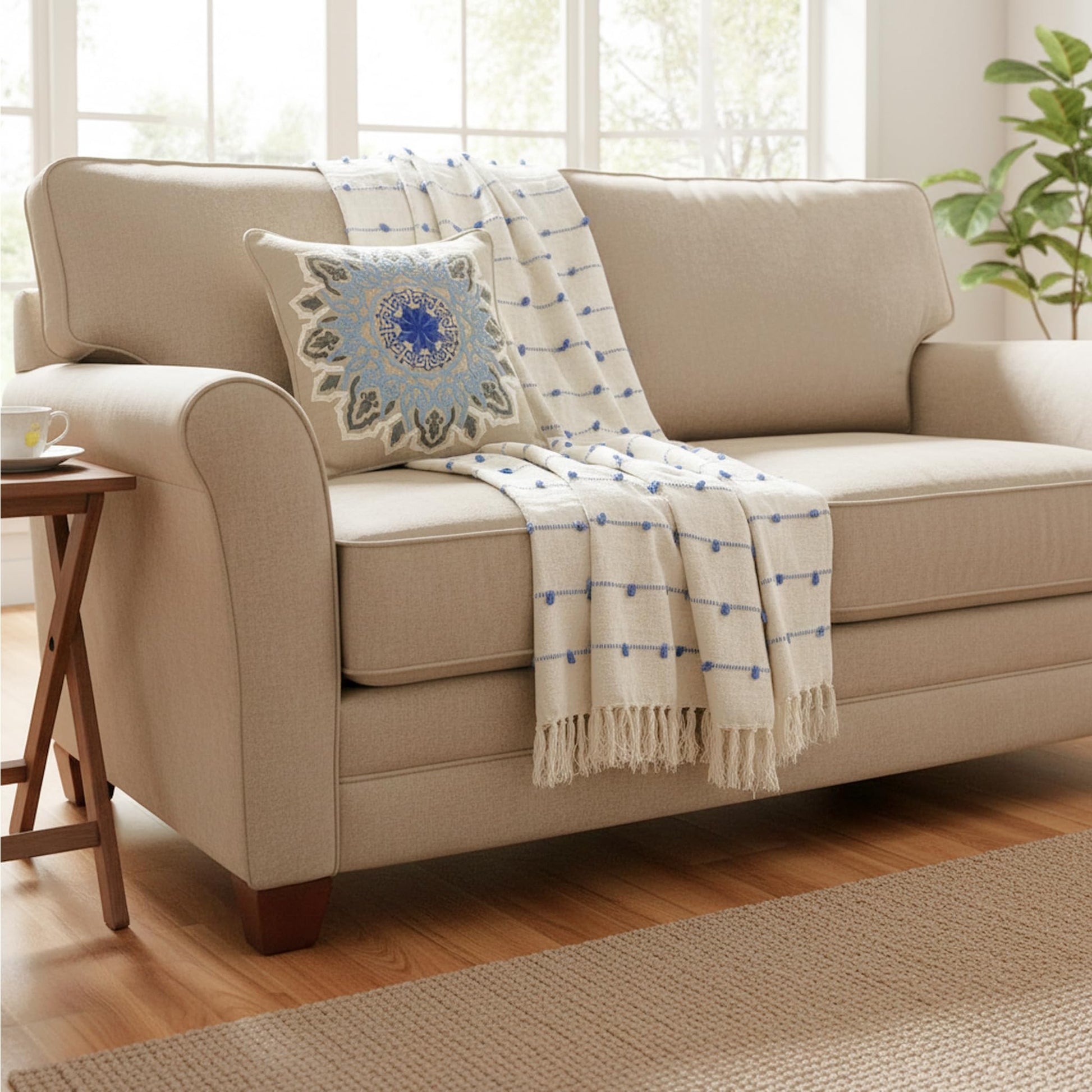 Beige sofa with a decorative blanket and pillow in a bright living room.
