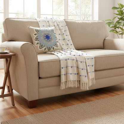 Beige sofa with a decorative blanket and pillow in a bright living room.