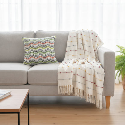 Gray sofa with a striped pillow and a patterned blanket in a living room setting.