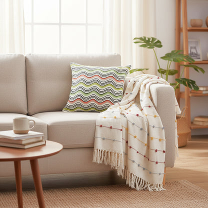 Cozy living room with a beige sofa, striped pillow, and blanket.