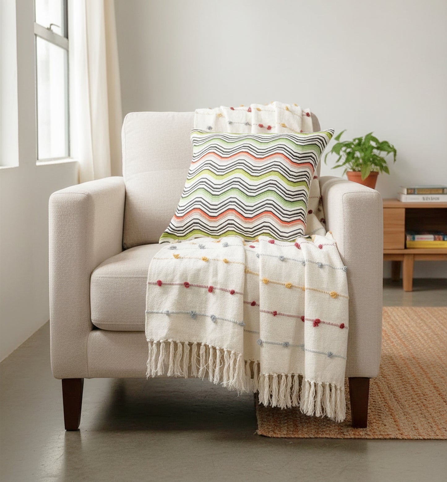 Beige armchair with a colorful pillow and blanket in a bright room.
